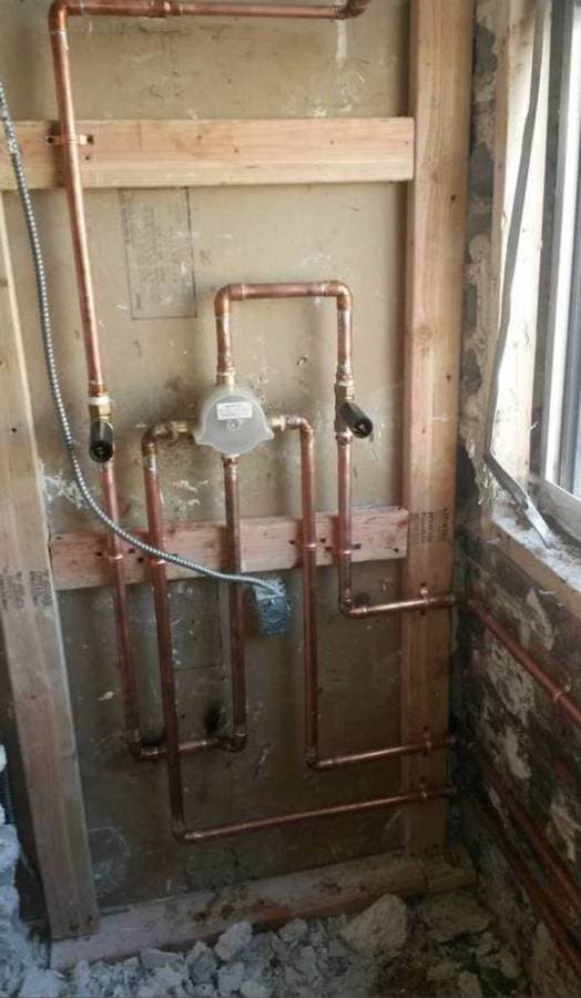 Newly installed gas meter and copper piping mounted on interior wall during plumbing installation